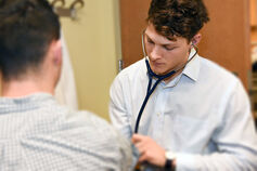 A medical student performs an exam with a stethoscope.